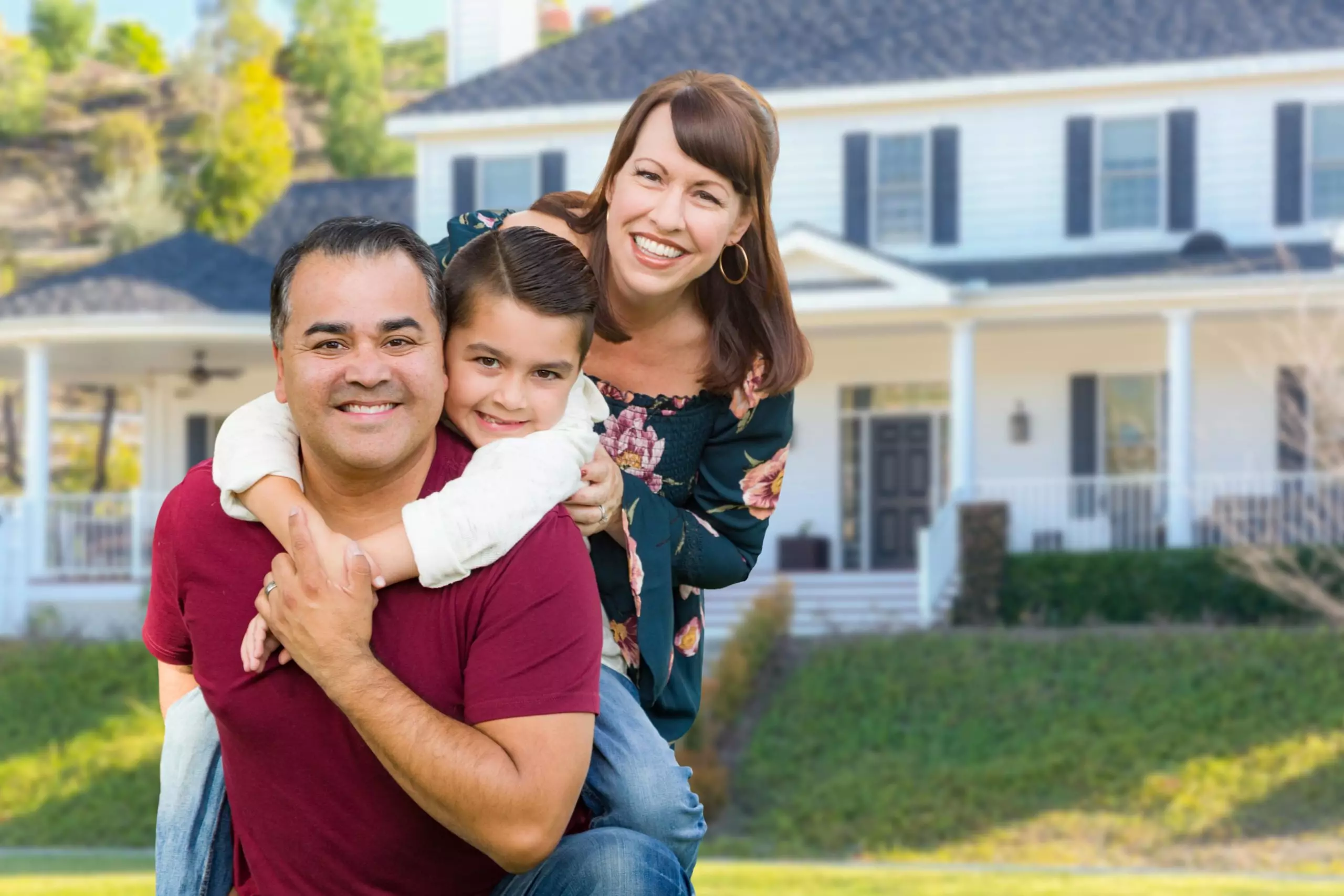 Smiling Family with there new home at the back